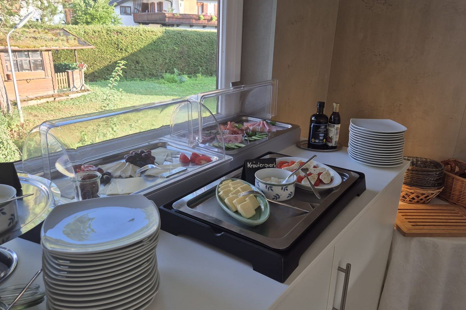Das Frühstücksbuffet mit Aufschnitt, Käse und Obst am Fenster