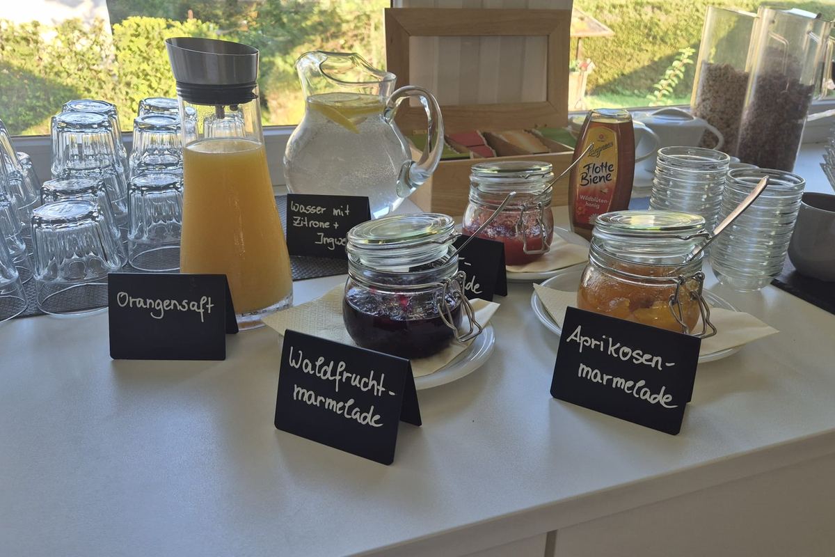 Waldfrucht- und Aprikosenmarmelade in Bügelgläsern, daneben Orangensaft